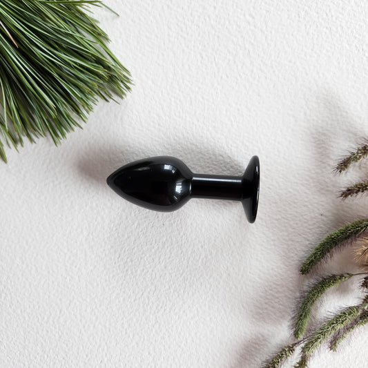 Obsidian butt-plug for anal pleasure in a white surface