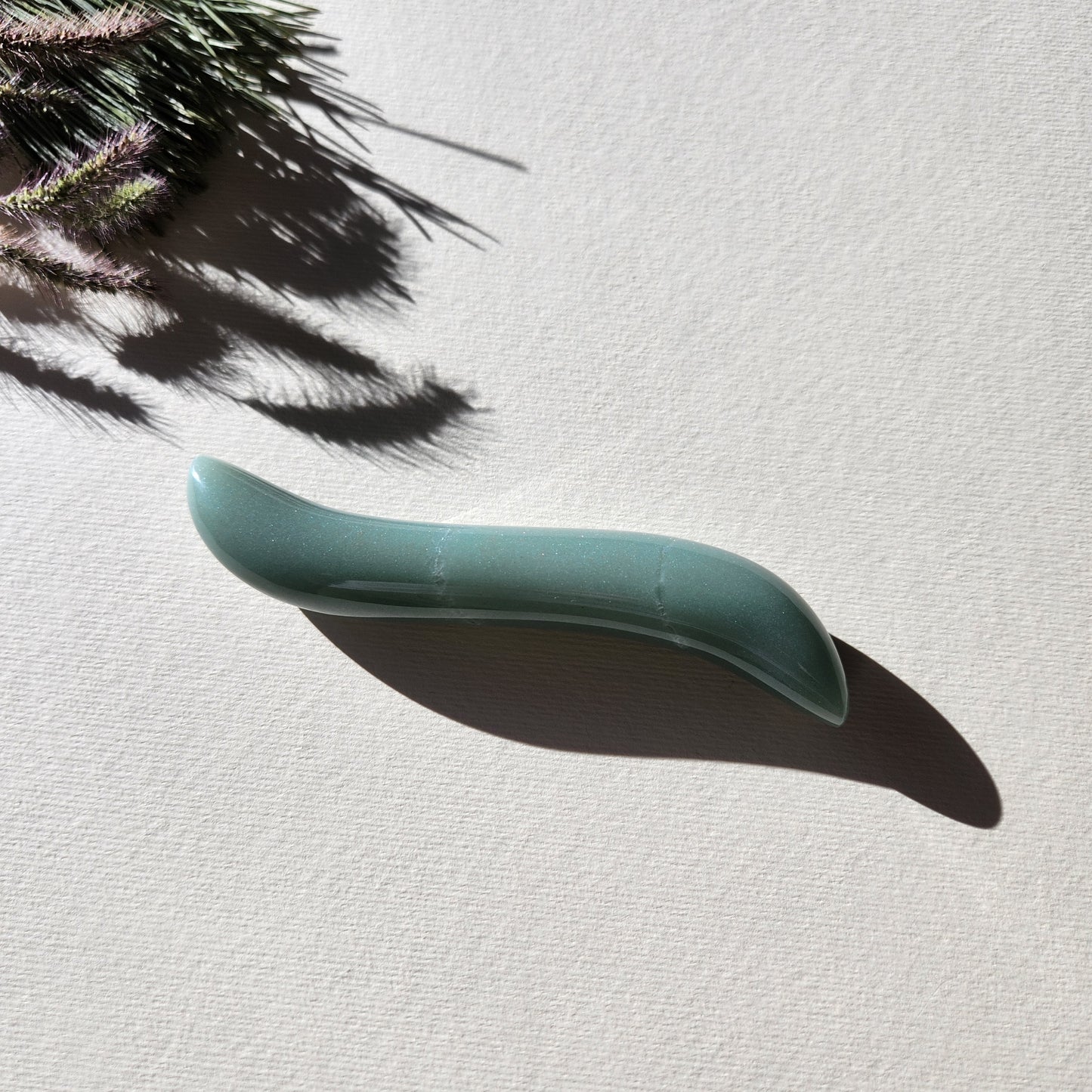 Crystal Yoni Wand Mini S-shape Green Aventurine for sexual stimulation in a white surface