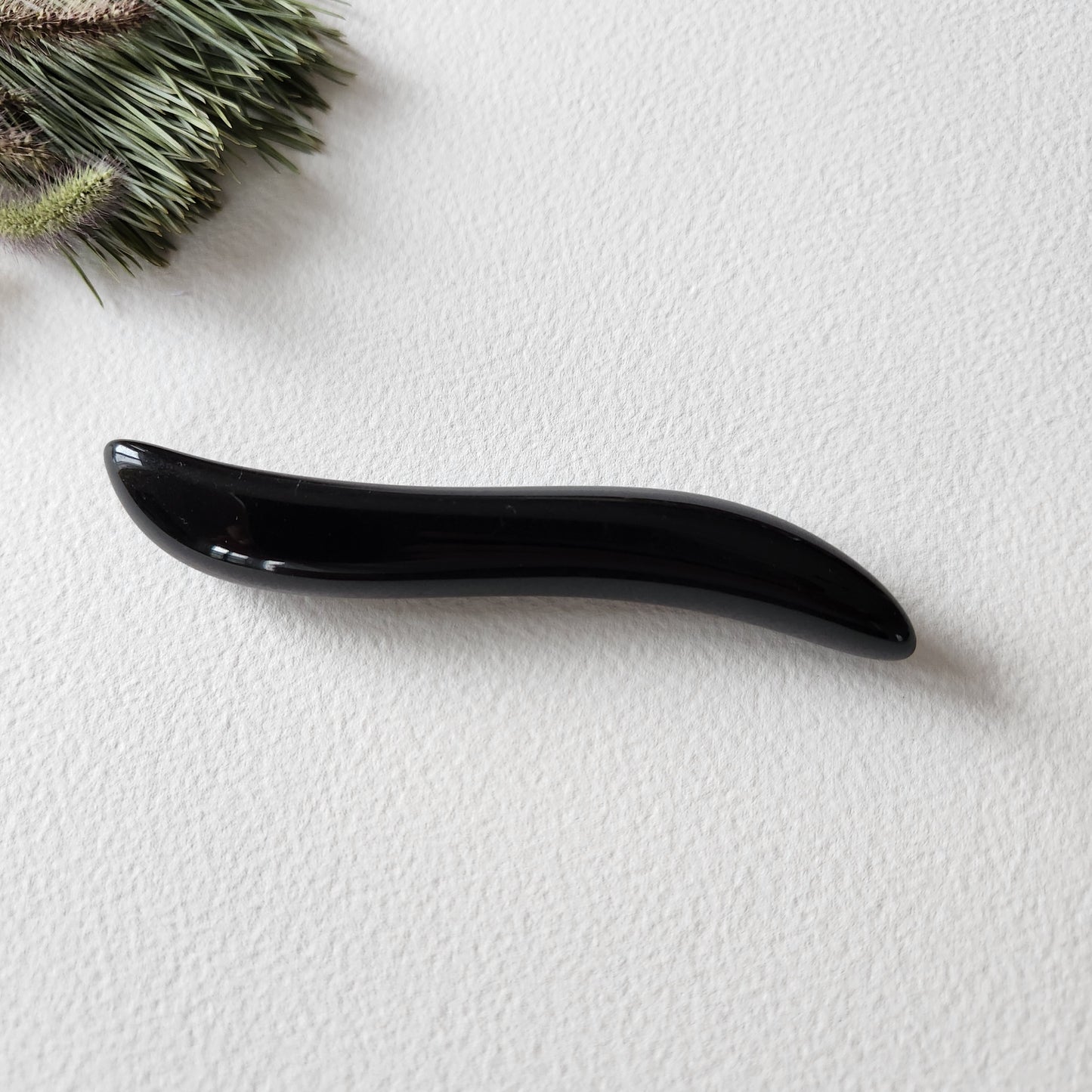 Crystal Wand Yoni mini S-Shape for sexual stimulation put on a white surface