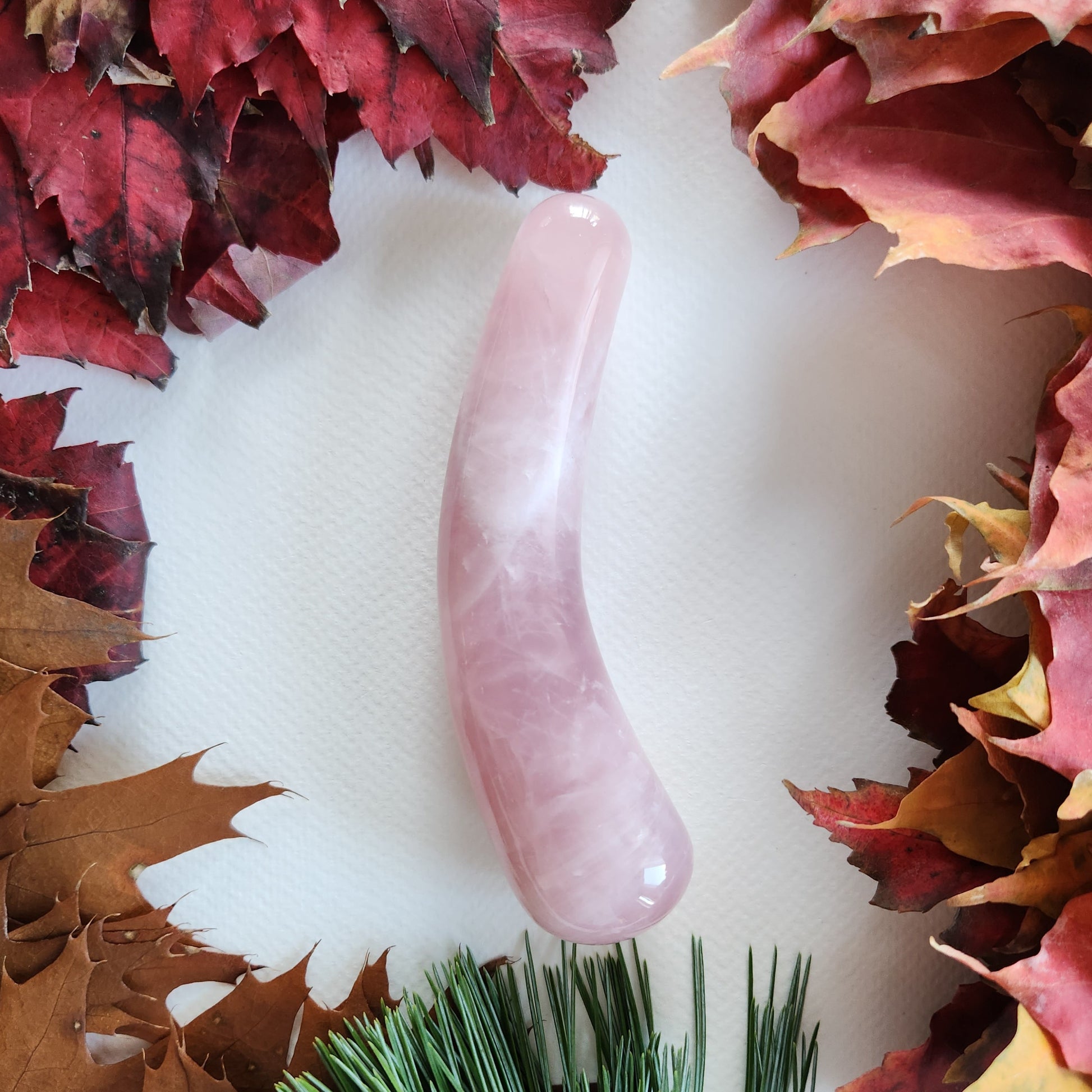 Close-up of a pink, curved rose quartz dildo wand for sex anal stimulation