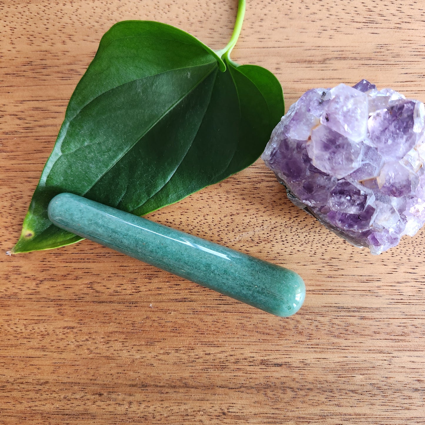 Crystal Wand Yoni mini green aventurine on a wood surface aside a leaf and a crystal rock