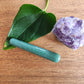 Crystal Wand Yoni mini green aventurine on a wood surface aside a leaf and a crystal rock