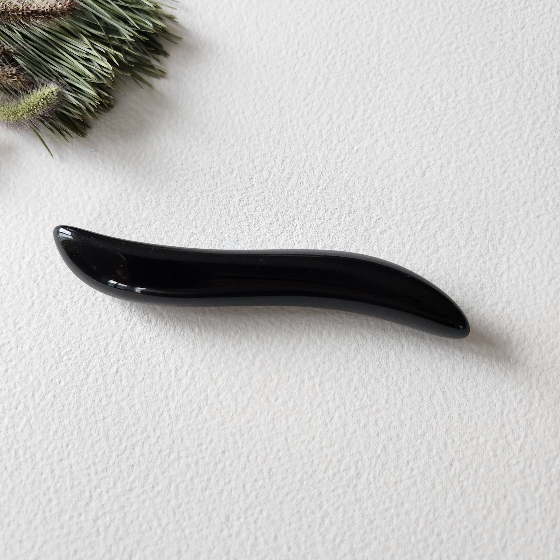 Crystal Wand Yoni mini S-Shape for sexual stimulation put on a white surface