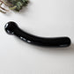 Close-up of a smooth, black curved obsidian crystal massage wand with round tip