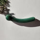 Crystal Wand Yoni Curved Green on a white surface in a shadow
