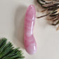 A long, smooth, pink Rose Quartz curved crystal massage wand, photographed on a neutral background.