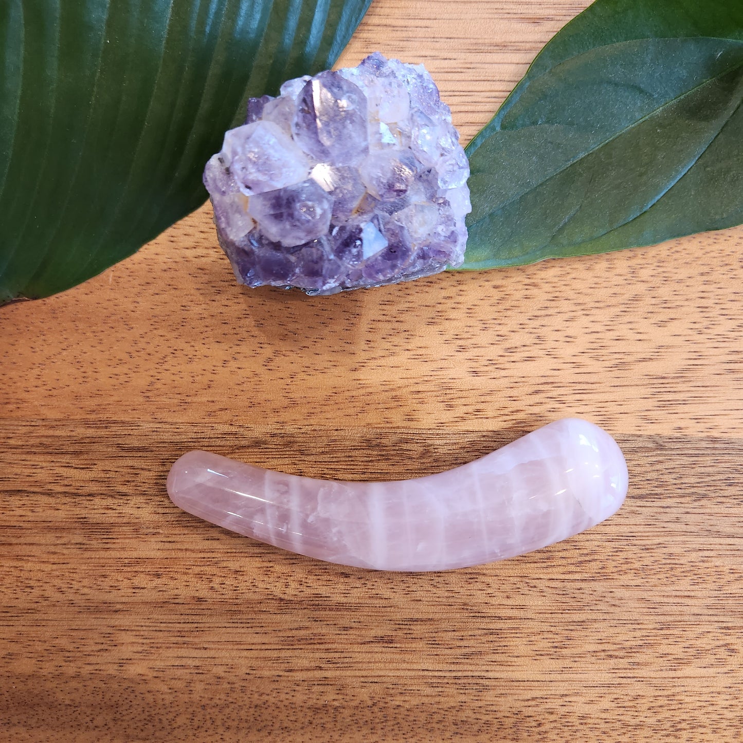 Ergonomically shaped rose quartz crystal wand for massage and self-care.
